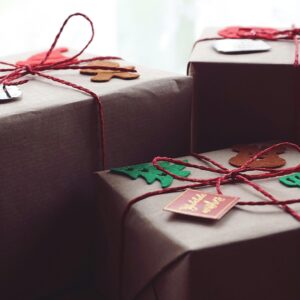 Three beautifully wrapped holiday gift packages with festive decorations.