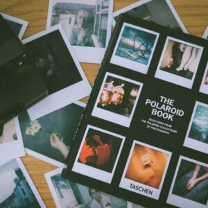 Collection of vintage Polaroid photos with an instant film camera on a wooden surface.