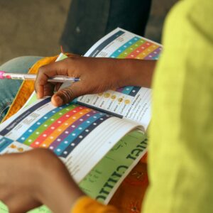 A child engages with a colorful educational booklet, holding a pen.
