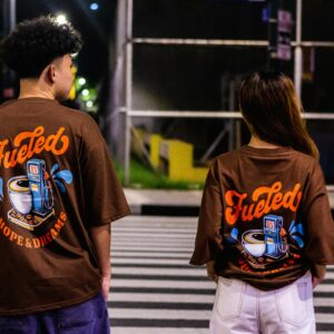 Couple wearing graphic T-shirts crossing a city street at night, showcasing urban fashion.