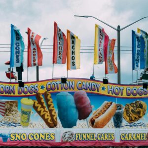 Brightly colored carnival stand selling various snacks such as corn dogs and cotton candy.