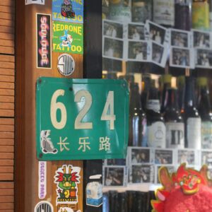 Street view of a bar with unique stickers and Chinese address sign.