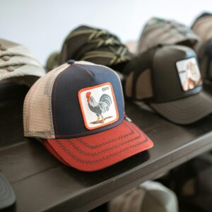 Collection of fashionable graphic caps displayed on a shelf, highlighting unique rooster design.
