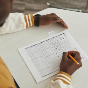 Focused student marking answers on a multiple choice exam sheet in a classroom setting.