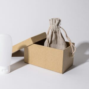 Minimalist photo of eco-friendly packaging with a cardboard box, pouch, and white plastic bottle.