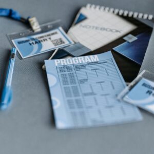 Close-up of conference materials including name tags, program, and pen on a gray surface.